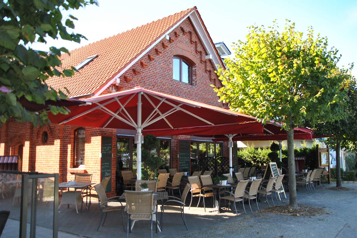 Außenansicht des Restaurants Bootshaus Binz mit Außenbereich, der mit Stühlen und Tischen ausgestattet ist.